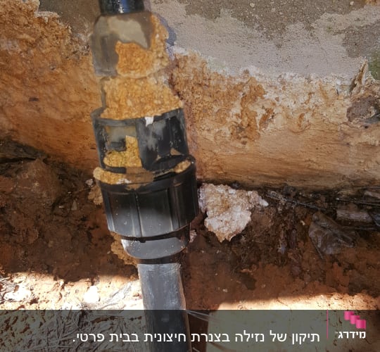 צינור שחור עם נזילה בקיר חיצוני